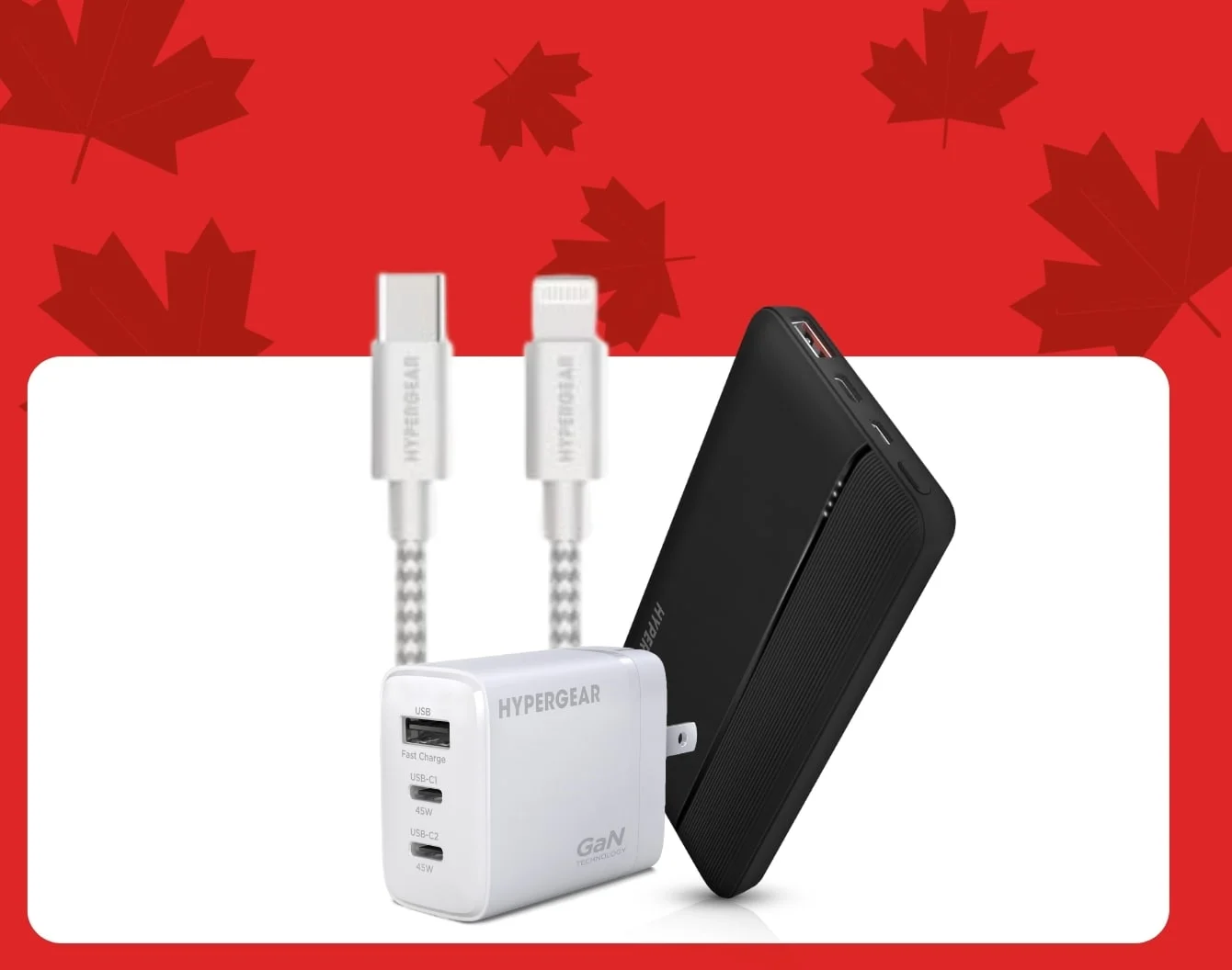 Hypergear cables inside a box behind a black Hypergear powerbank next to a white Hypergear phone charging block inside a white container against a red background covered in dark red maple leaves.